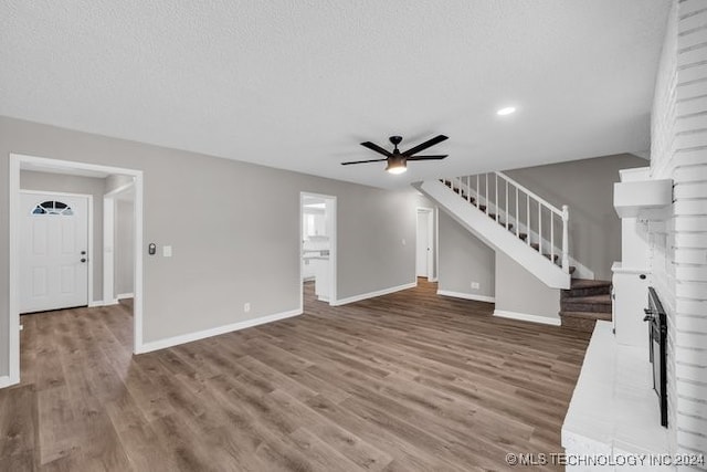 unfurnished living room with hardwood / wood-style flooring, ceiling fan, and a textured ceiling