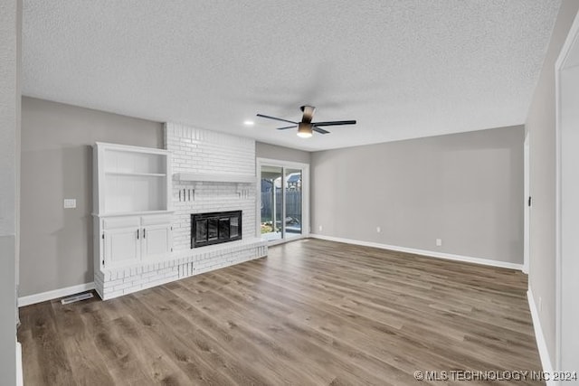 unfurnished living room featuring ceiling fan, hardwood / wood-style flooring, a fireplace, and a textured ceiling