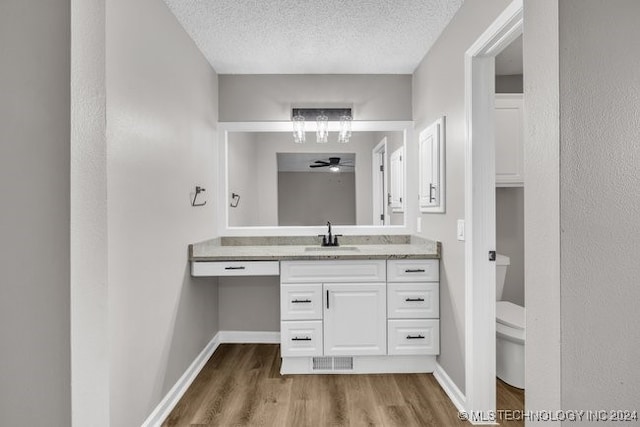 bathroom featuring hardwood / wood-style flooring, vanity, toilet, and a textured ceiling