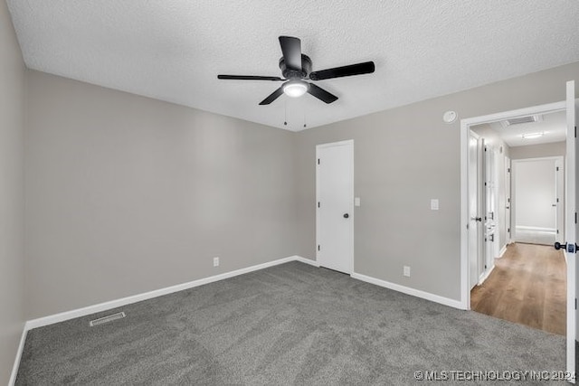 carpeted spare room featuring ceiling fan and a textured ceiling