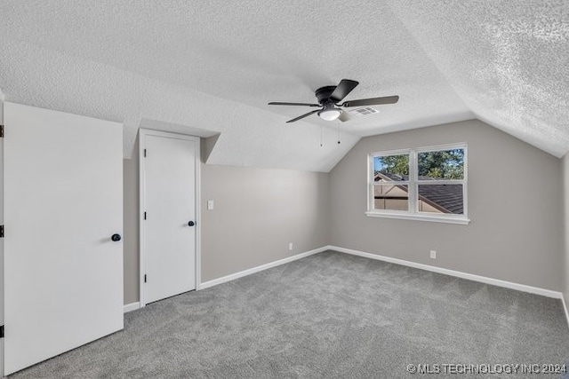 additional living space with vaulted ceiling, carpet, a textured ceiling, and ceiling fan