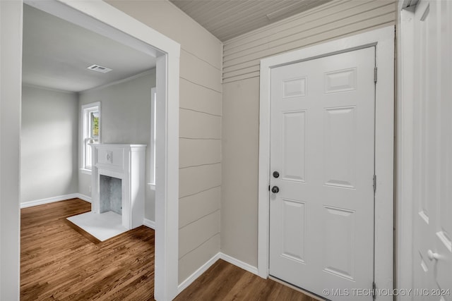 entryway with hardwood / wood-style flooring, wooden walls, and crown molding