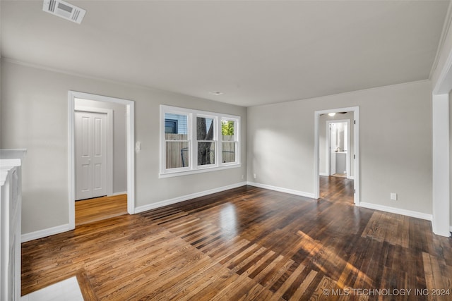 empty room with dark hardwood / wood-style floors and crown molding