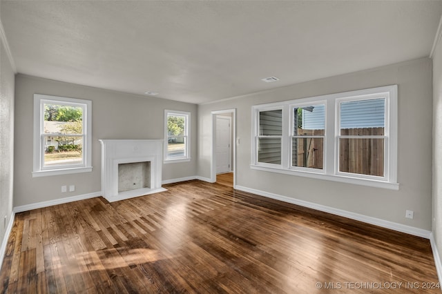 unfurnished living room with wood-type flooring, ornamental molding, and a healthy amount of sunlight