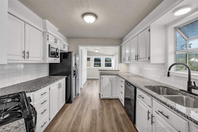 kitchen with white cabinets, sink, wood-type flooring, black appliances, and decorative backsplash