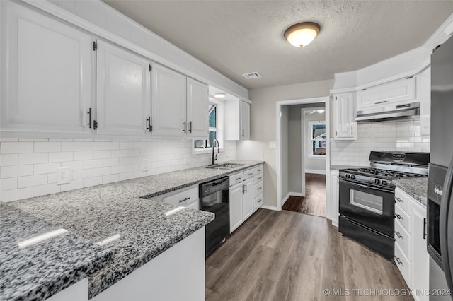 kitchen featuring black appliances, sink, dark hardwood / wood-style flooring, dark stone counters, and white cabinetry