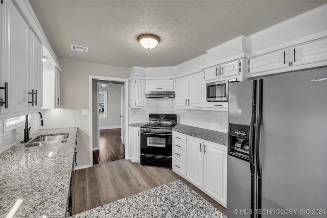 kitchen with light stone counters, sink, light hardwood / wood-style floors, white cabinetry, and appliances with stainless steel finishes