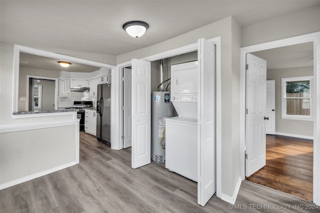 clothes washing area featuring stacked washer and clothes dryer, light wood-type flooring, and water heater