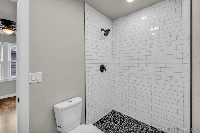 bathroom with ceiling fan, hardwood / wood-style flooring, tiled shower, and toilet