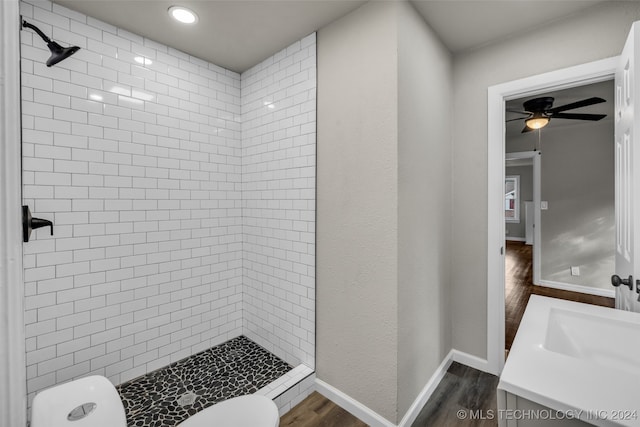 bathroom featuring a tile shower, ceiling fan, vanity, wood-type flooring, and toilet