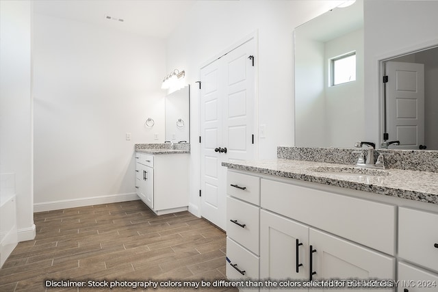 bathroom featuring hardwood / wood-style flooring, a washtub, and vanity