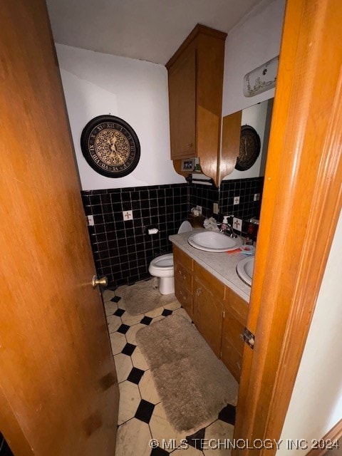 bathroom featuring tile patterned flooring, tile walls, vanity, and toilet