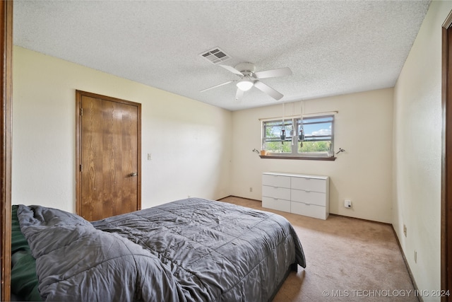 bedroom with a textured ceiling, ceiling fan, and light carpet