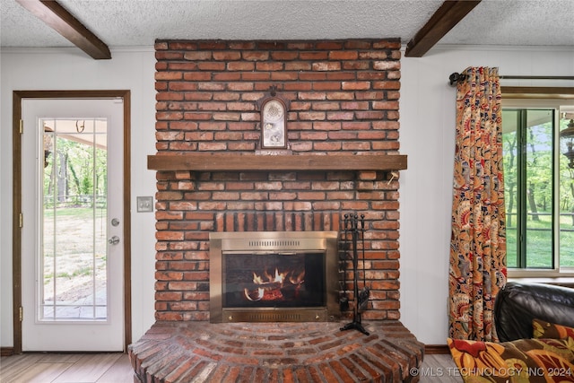 unfurnished living room featuring hardwood / wood-style floors, a textured ceiling, a brick fireplace, and beam ceiling