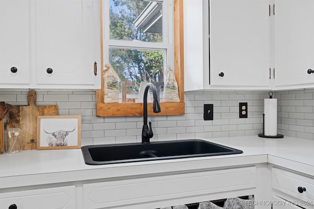 kitchen featuring white cabinets, backsplash, and sink