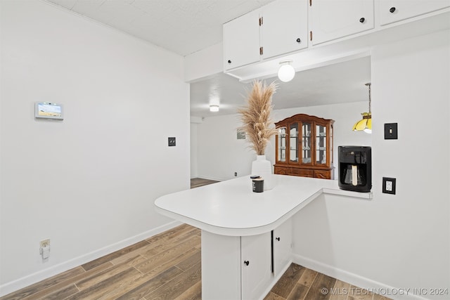 kitchen with kitchen peninsula, hardwood / wood-style flooring, decorative light fixtures, and white cabinets