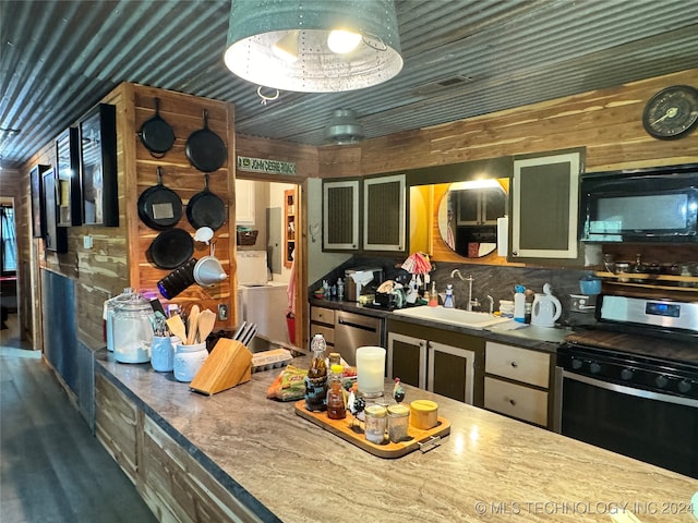 kitchen featuring wood walls, green cabinets, sink, decorative backsplash, and appliances with stainless steel finishes