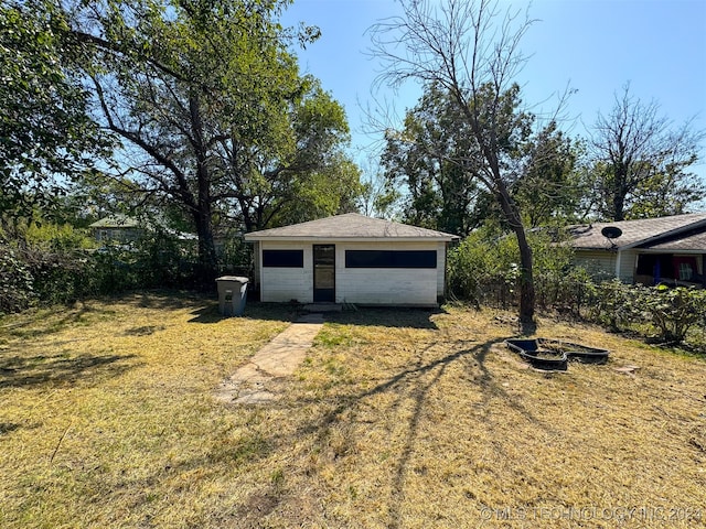 view of yard with a garage, a fire pit, and an outdoor structure