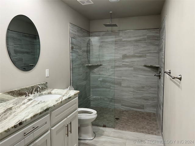 bathroom featuring vanity, toilet, and a tile shower