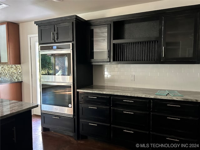 kitchen featuring tasteful backsplash, light stone countertops, double oven, and dark hardwood / wood-style floors