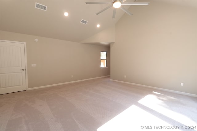 spare room with ceiling fan, high vaulted ceiling, and light carpet