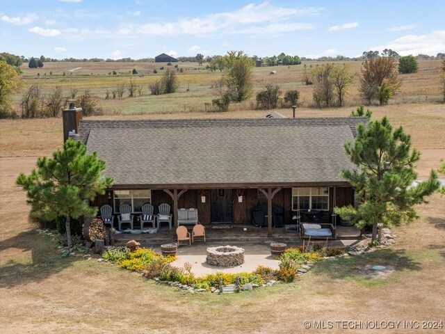 back of property with an outdoor fire pit, a rural view, and a patio area