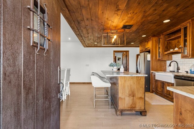 kitchen with wood ceiling, tasteful backsplash, a kitchen breakfast bar, stainless steel appliances, and a center island