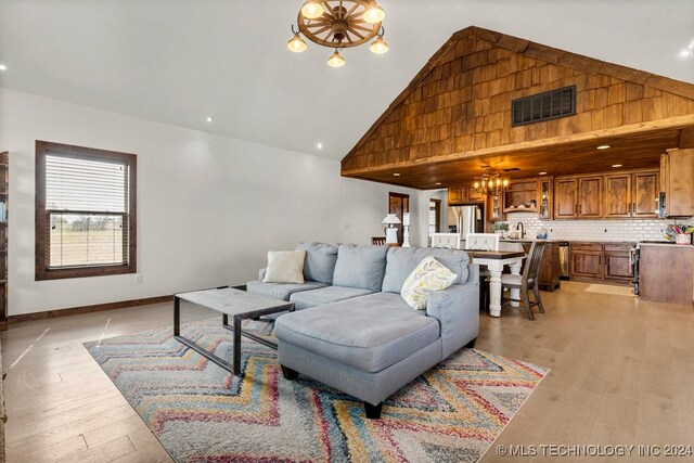 living room with light hardwood / wood-style floors, high vaulted ceiling, and an inviting chandelier