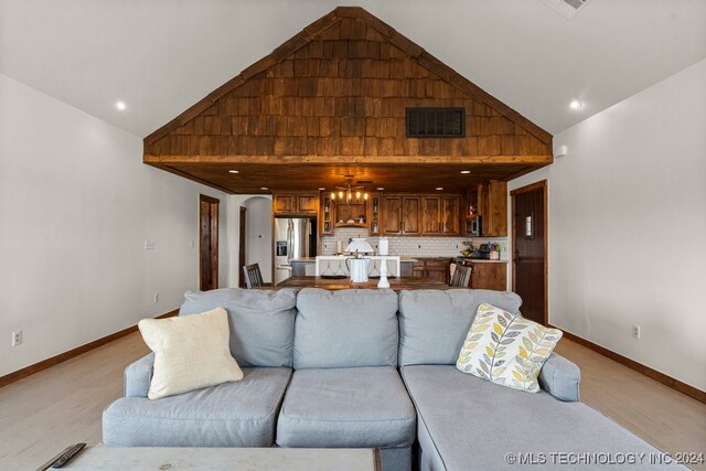 living room with light colored carpet, a chandelier, and high vaulted ceiling