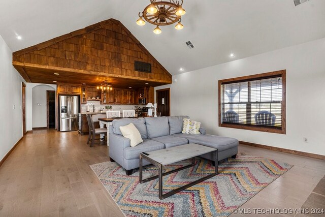 living room featuring an inviting chandelier, high vaulted ceiling, and light hardwood / wood-style flooring