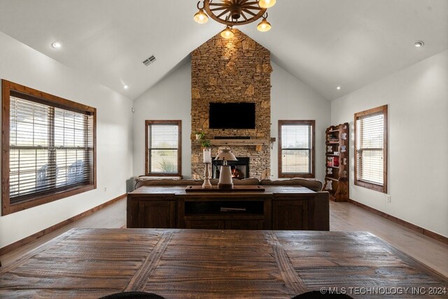 living room featuring high vaulted ceiling and a stone fireplace