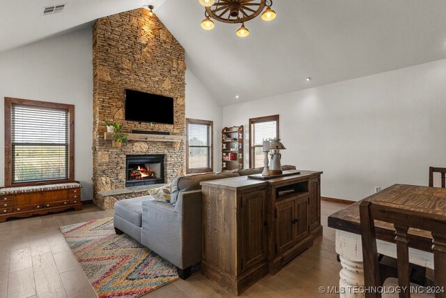 living room featuring hardwood / wood-style flooring, high vaulted ceiling, and a stone fireplace