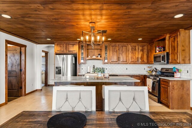 kitchen featuring a kitchen island, hanging light fixtures, stainless steel appliances, and backsplash