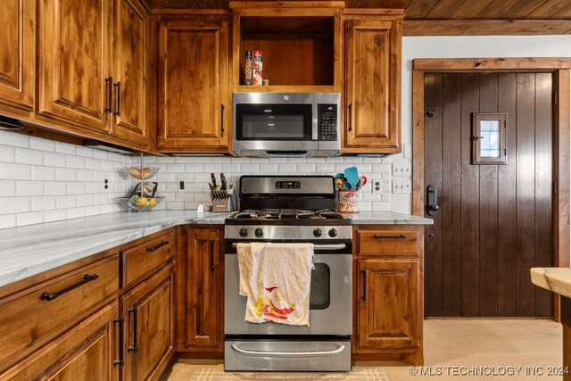 kitchen featuring backsplash, appliances with stainless steel finishes, and light stone counters