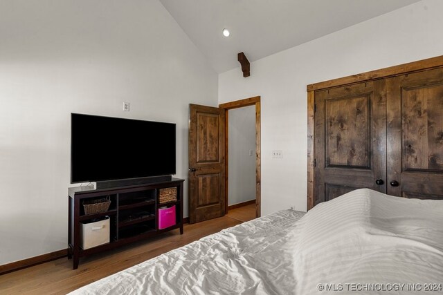 bedroom featuring light hardwood / wood-style flooring, a closet, and high vaulted ceiling