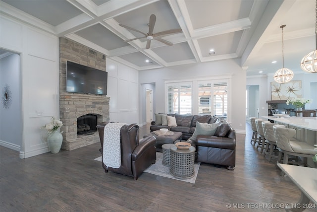 living room featuring coffered ceiling, beam ceiling, a stone fireplace, and dark hardwood / wood-style floors