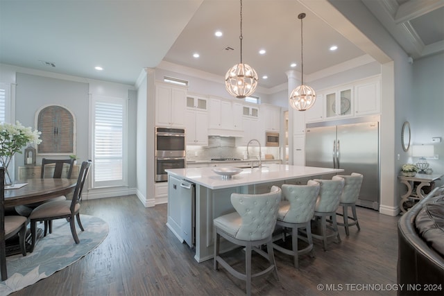 kitchen with a spacious island, white cabinets, built in appliances, and hanging light fixtures