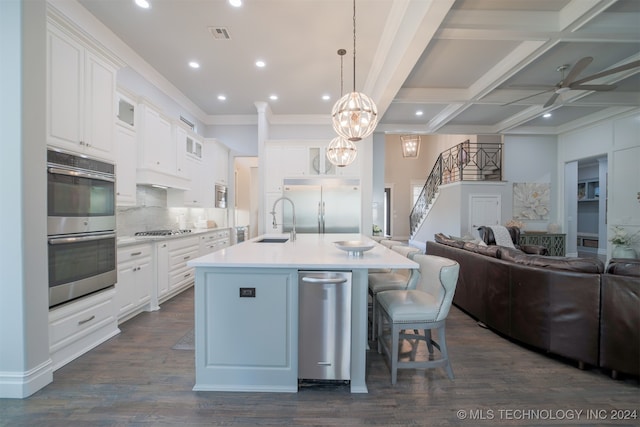 kitchen with white cabinets, a center island with sink, and decorative light fixtures