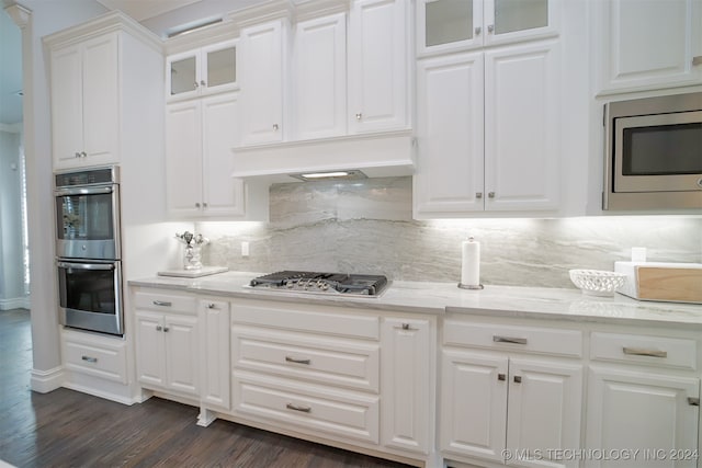 kitchen featuring tasteful backsplash, white cabinets, dark hardwood / wood-style flooring, custom exhaust hood, and appliances with stainless steel finishes