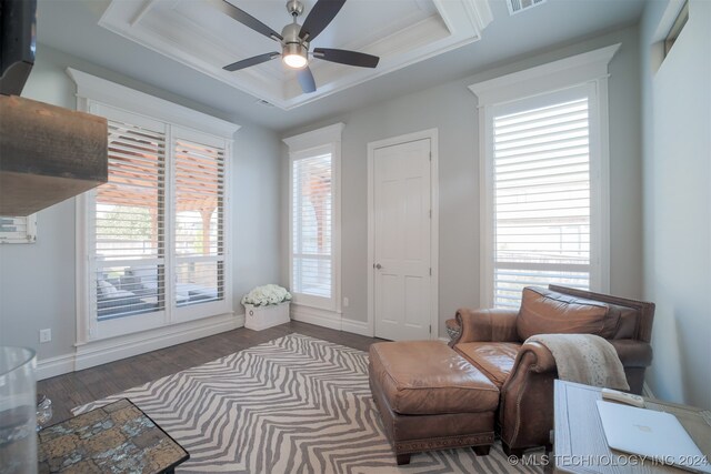 living area featuring ceiling fan, a tray ceiling, plenty of natural light, and dark wood-type flooring