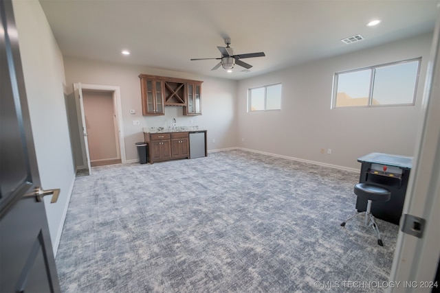 interior space featuring bar, light colored carpet, and ceiling fan