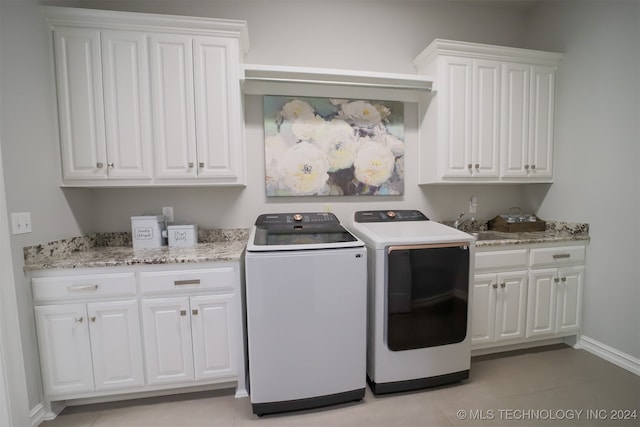 laundry room with light tile patterned flooring, washing machine and clothes dryer, sink, and cabinets