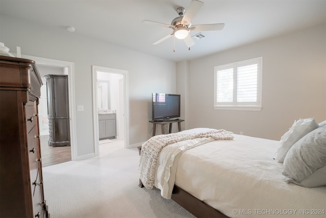 bedroom with light carpet, connected bathroom, and ceiling fan