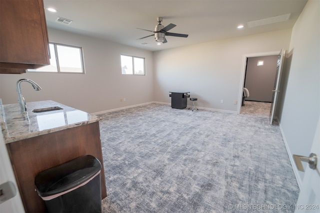 interior space with light stone counters, ceiling fan, sink, and carpet flooring