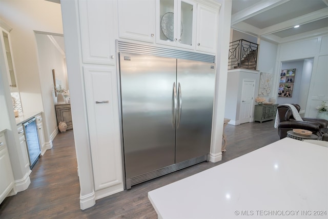 kitchen with white cabinets, dark hardwood / wood-style floors, beam ceiling, and built in fridge