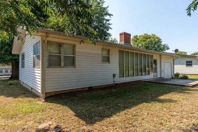 back of house with a patio and a lawn