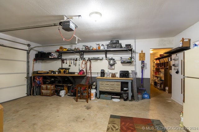 garage featuring a garage door opener, white refrigerator, and a workshop area