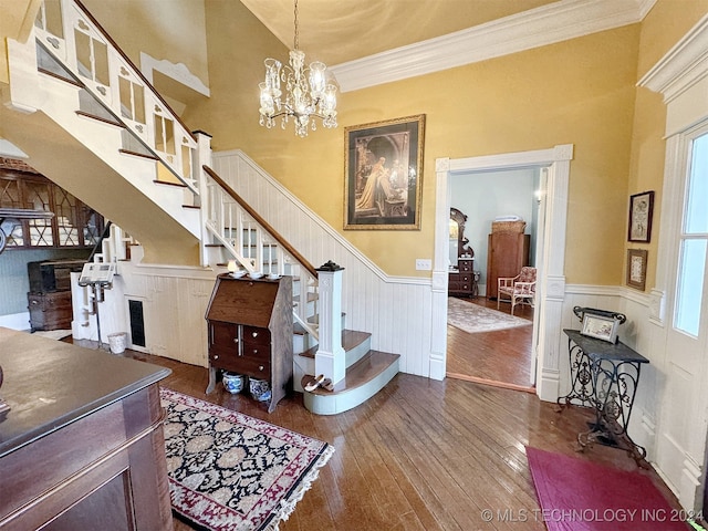 staircase featuring a notable chandelier, hardwood / wood-style flooring, a towering ceiling, and ornamental molding