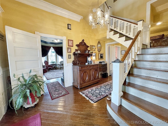 foyer entrance featuring a high ceiling, crown molding, dark wood-type flooring, and a chandelier