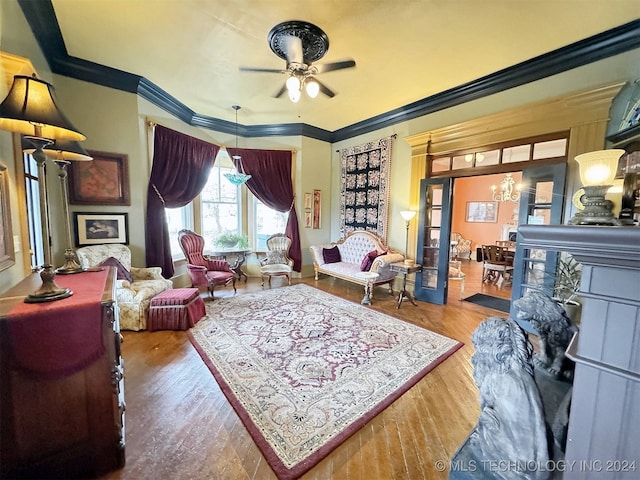 living room featuring ceiling fan with notable chandelier, crown molding, and hardwood / wood-style floors